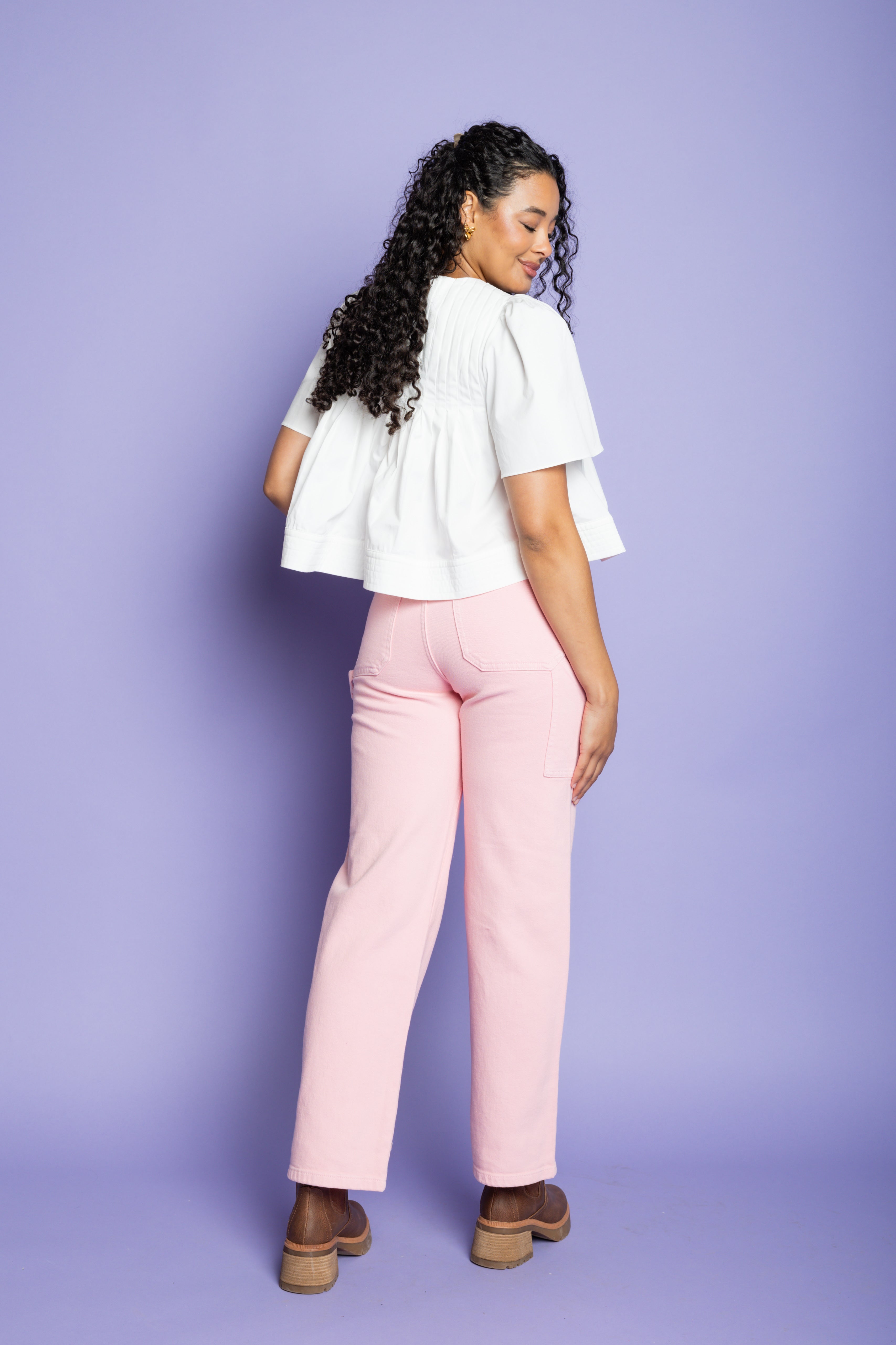 Model is wearing a white flowy short-sleeve blouse with pink straight leg pants.