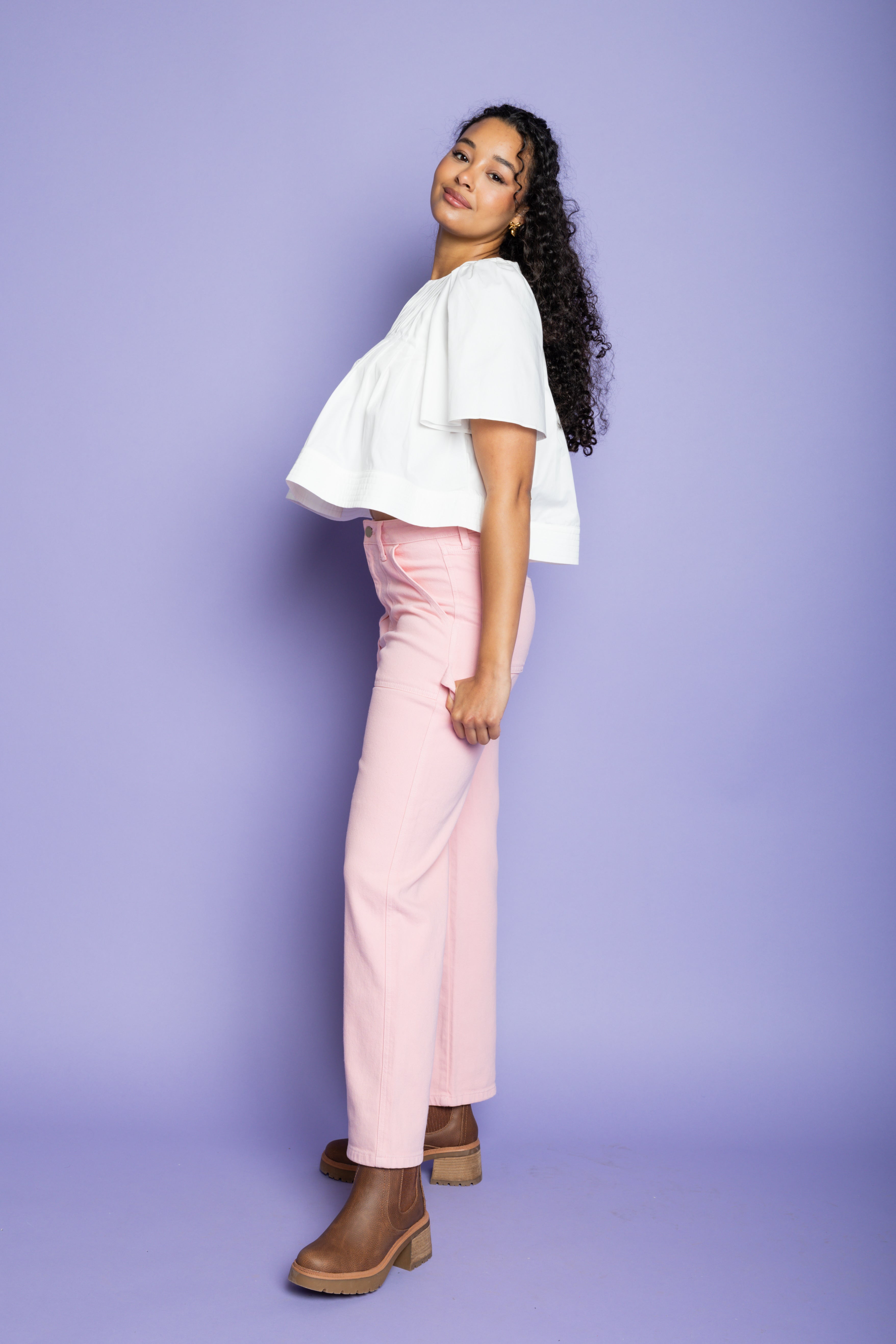 Model is wearing a white flowy short-sleeve blouse with pink straight leg pants.