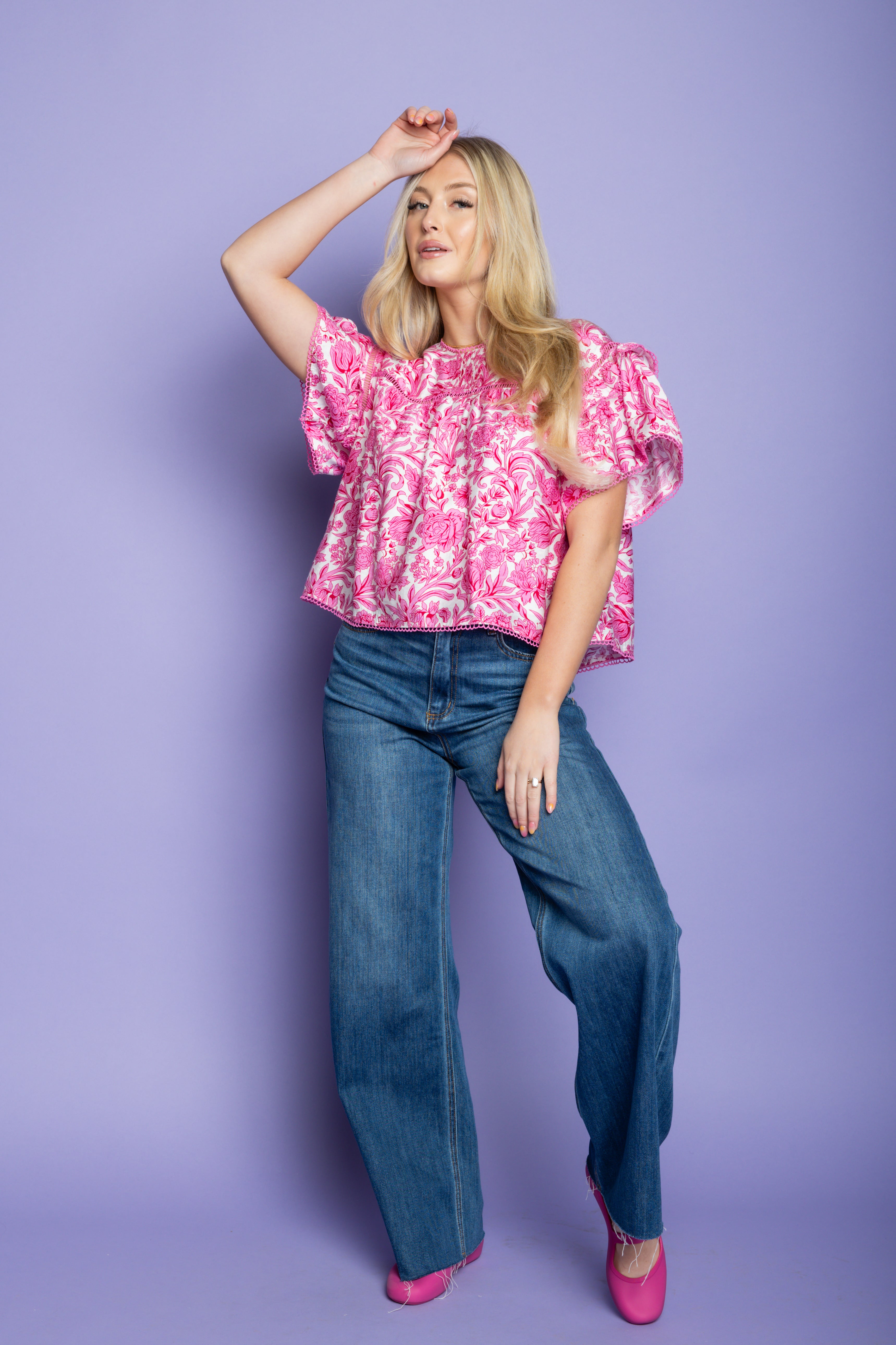 Model wearing pink short sleeve top and blue jeans with pink flats