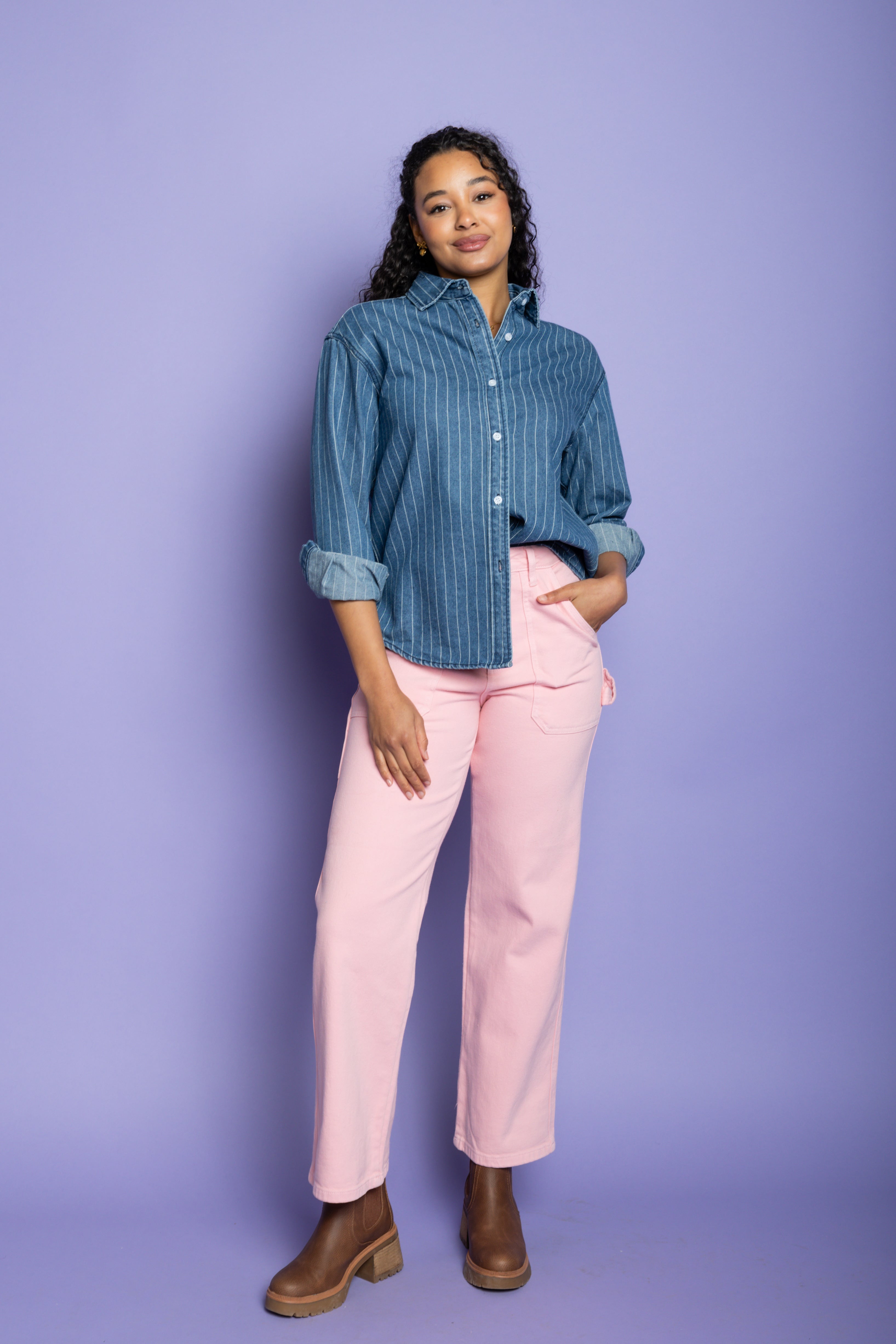 Model is wearing denim striped shirt with pink pants 