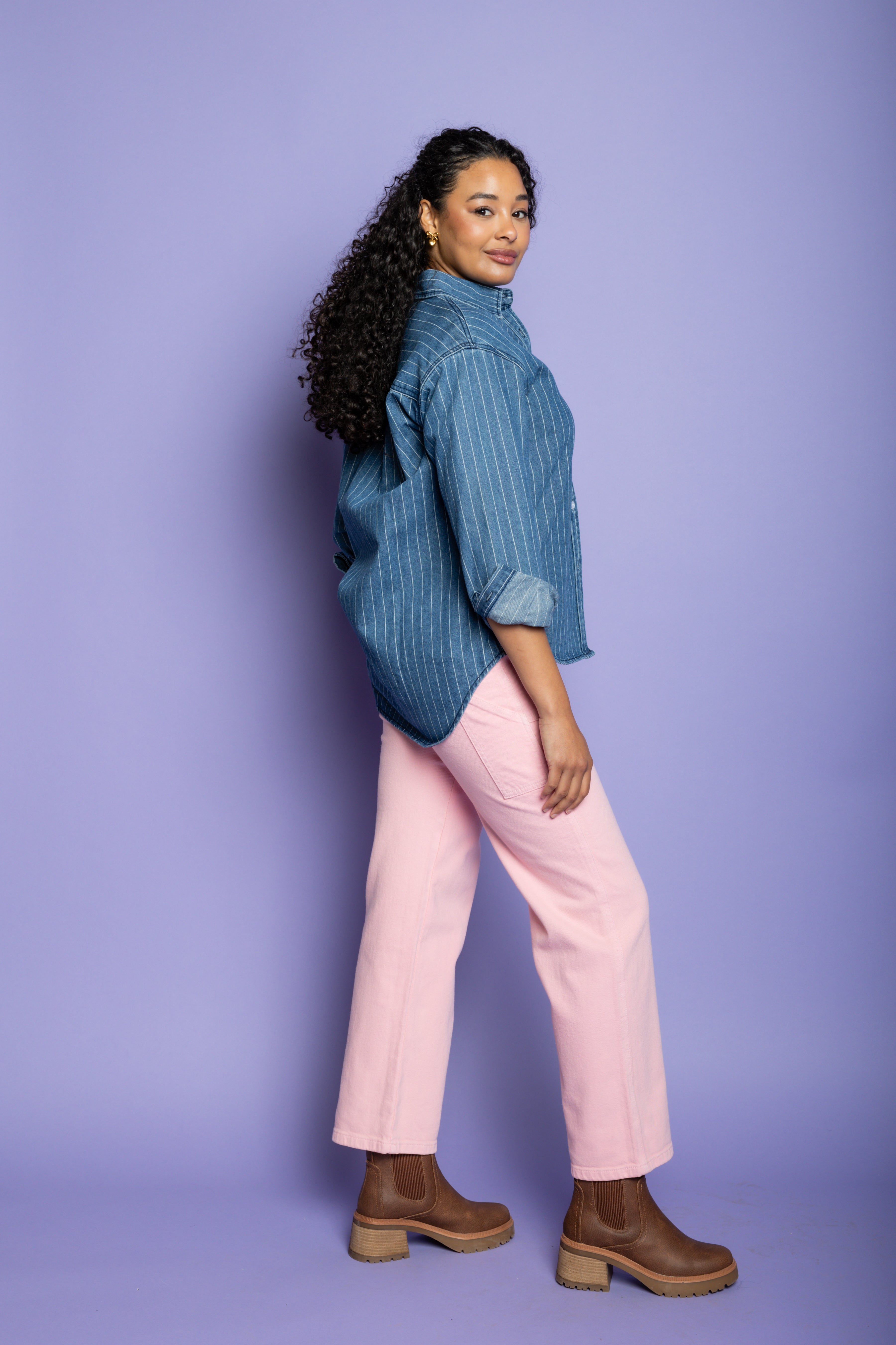 Model is wearing denim striped shirt with pink pants