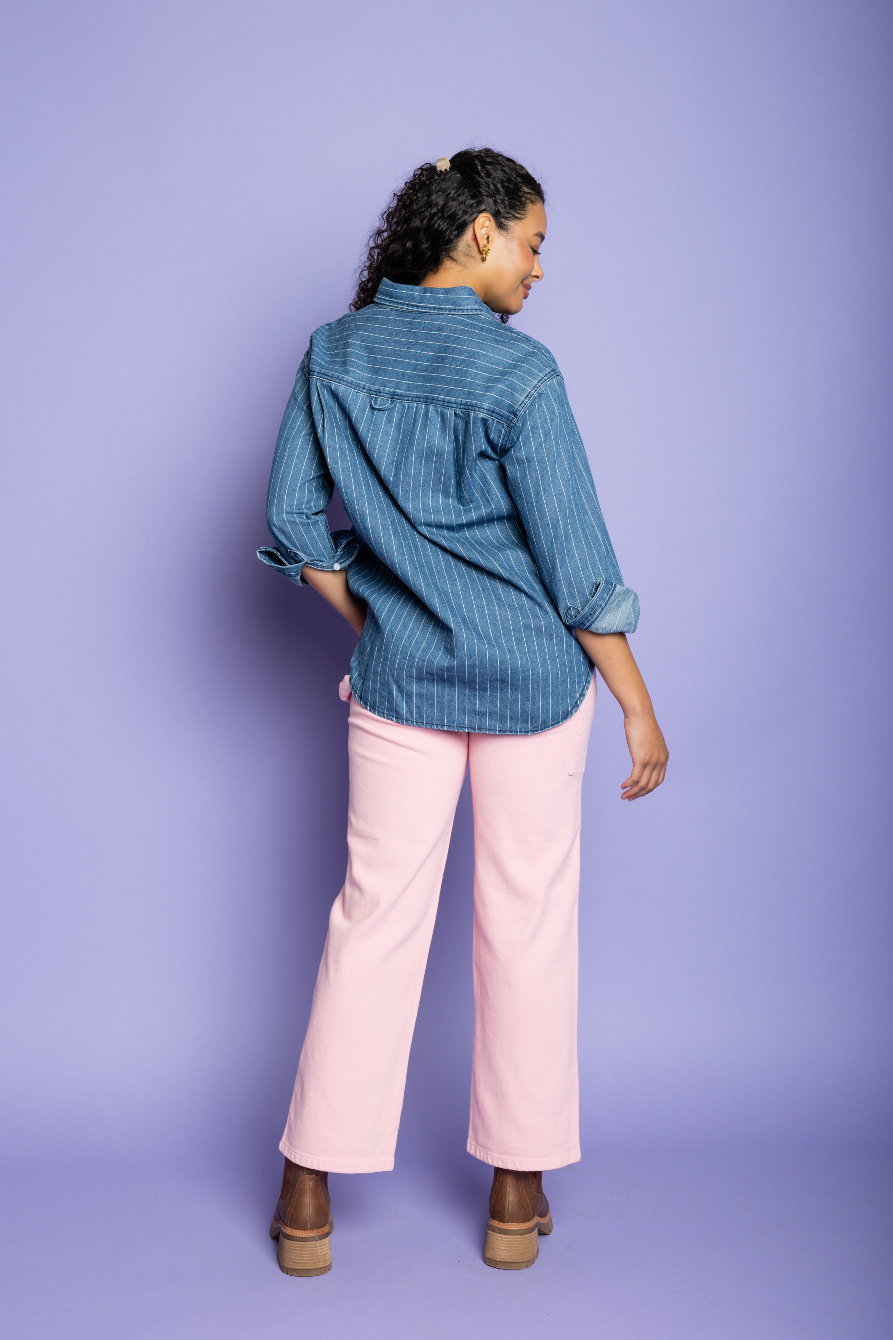 Model is wearing denim striped shirt with pink pants