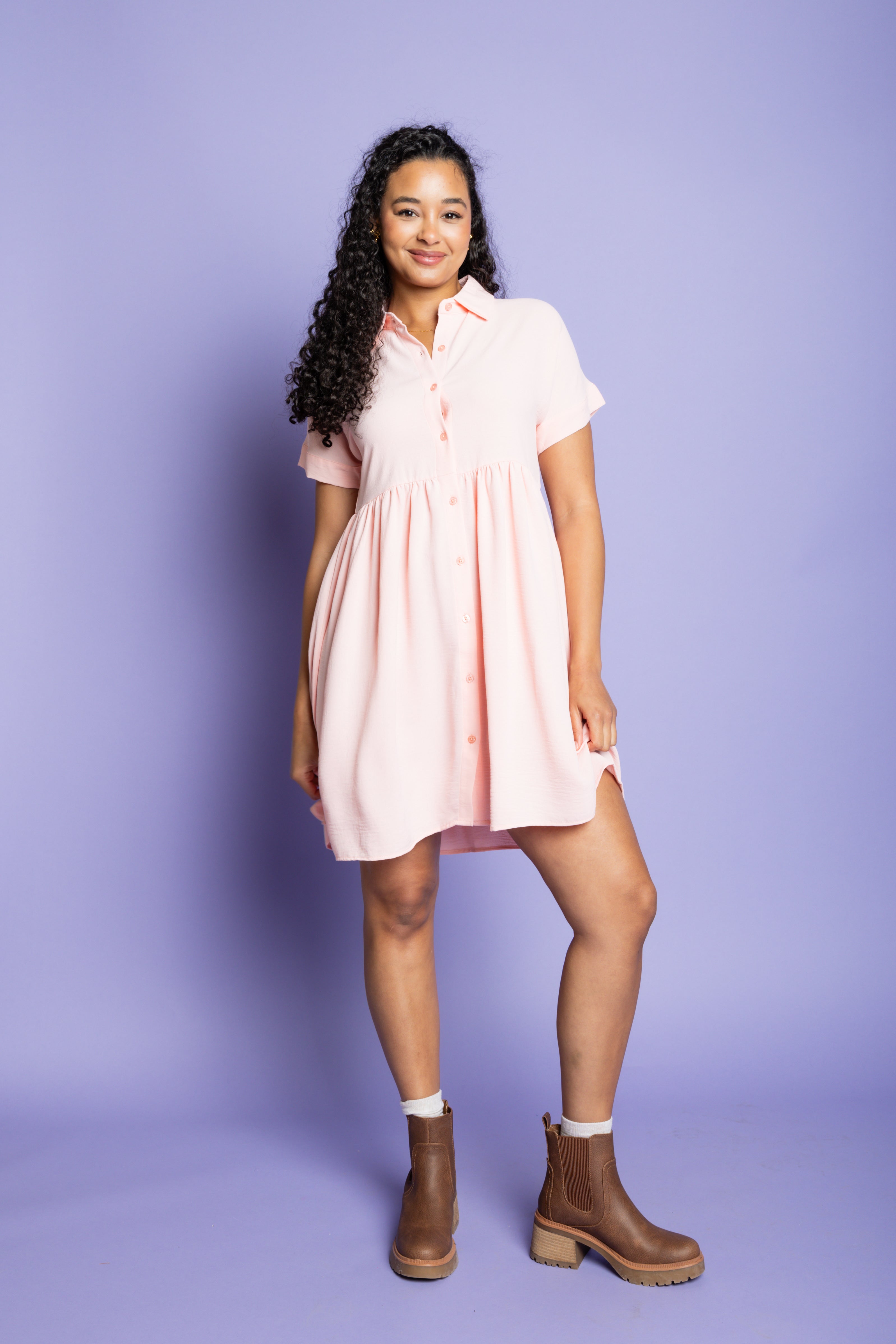 Model wearing collared button up mini dress with brown boots.