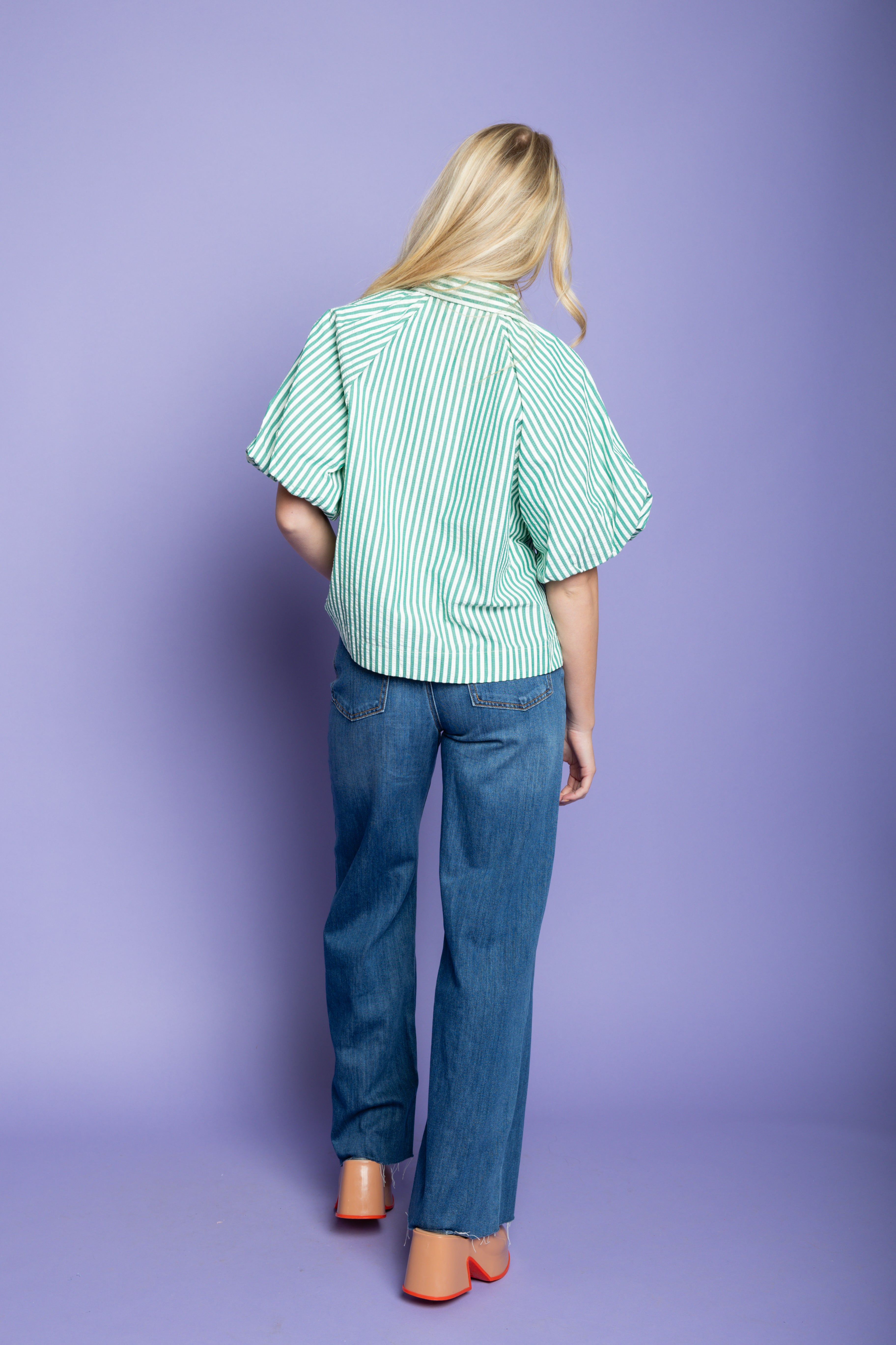 Model is wearing a striped puffer blouses with jeans.