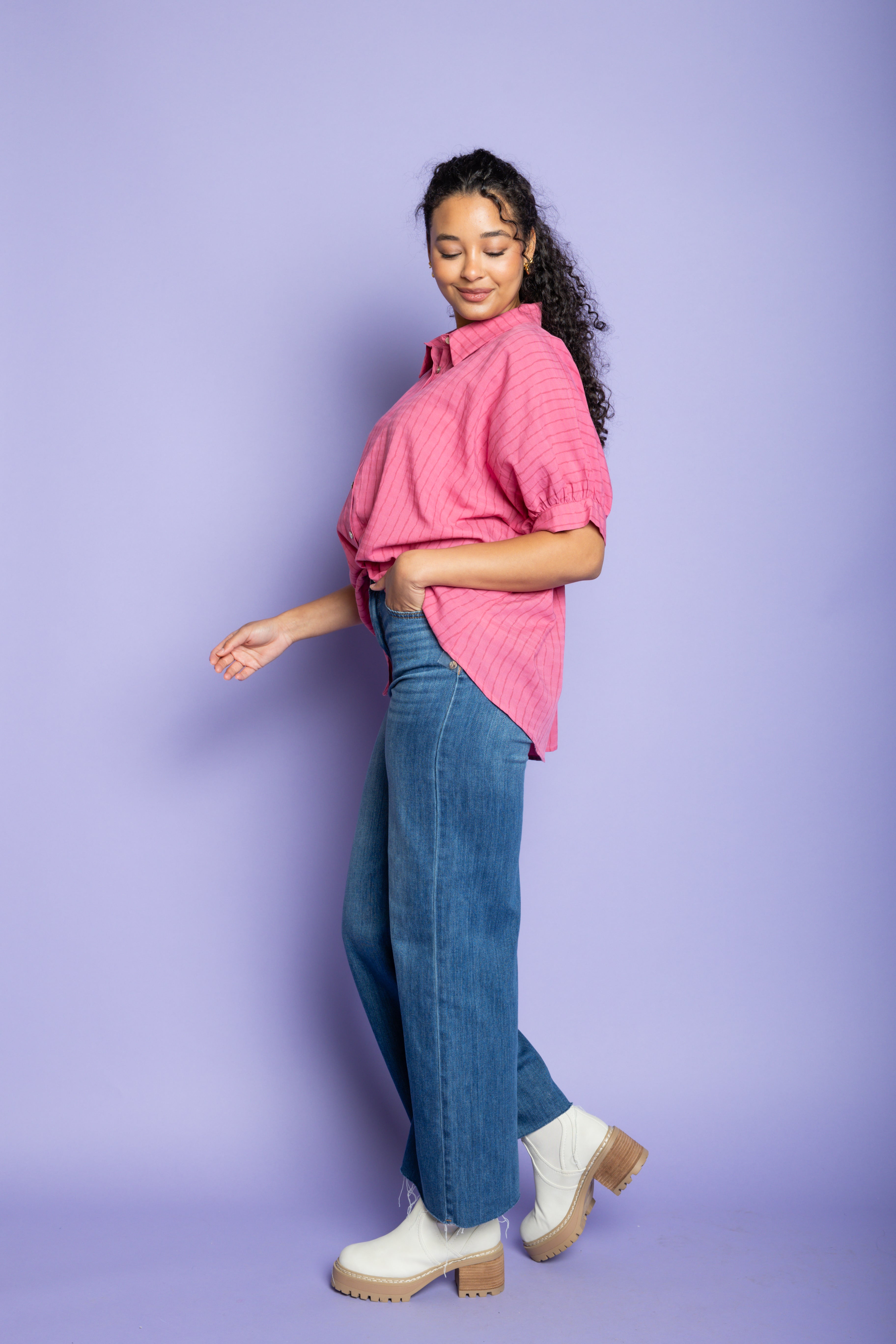 Model wearing pink oversized blouse with blue jeans and boots.