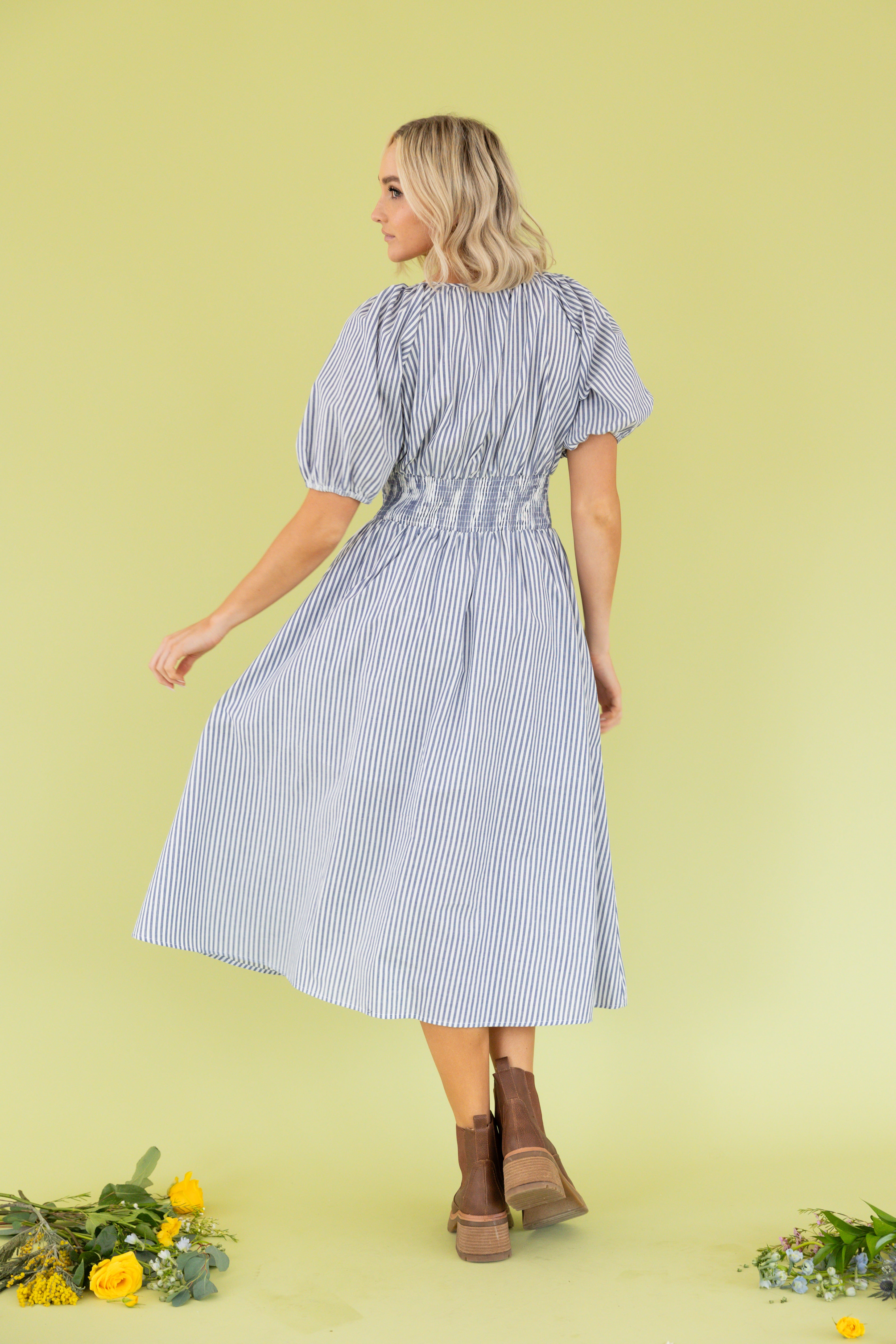 Model is wearing midi blue and white dress with sweetheart neckline. 