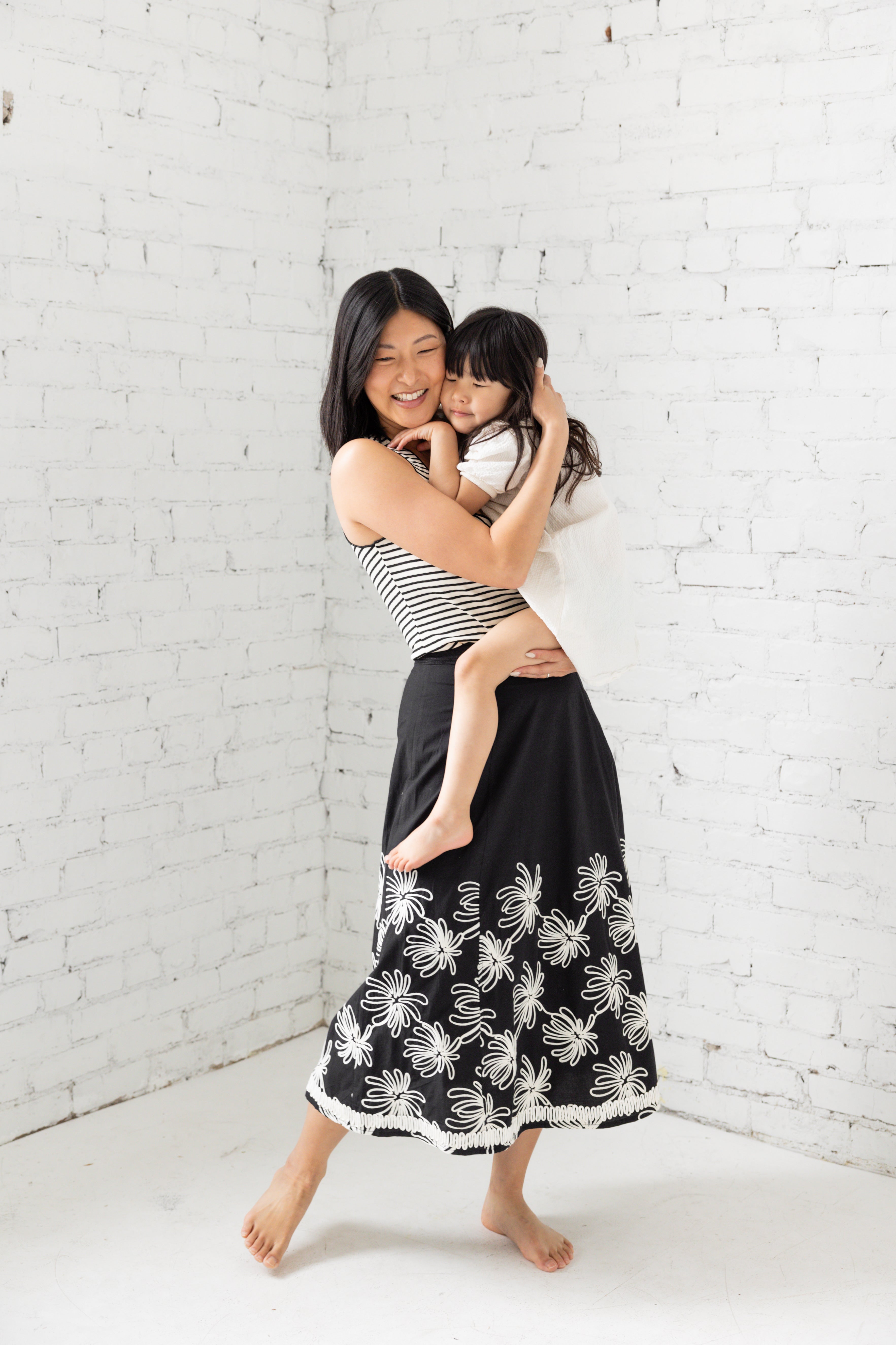 Model is wearing a midi black skirt with floral embroidery. 
