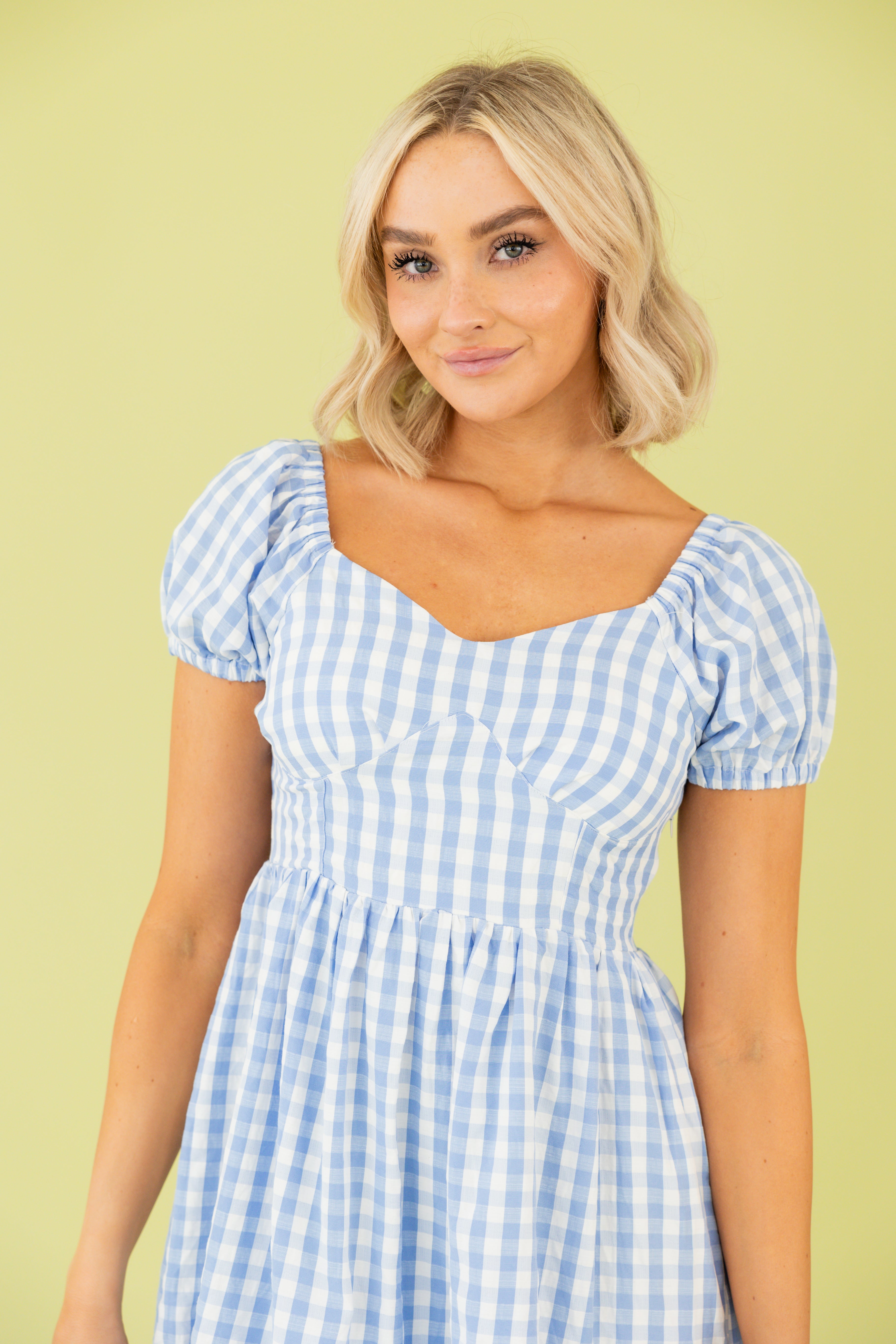 Model is wearing a mini gingham dress.