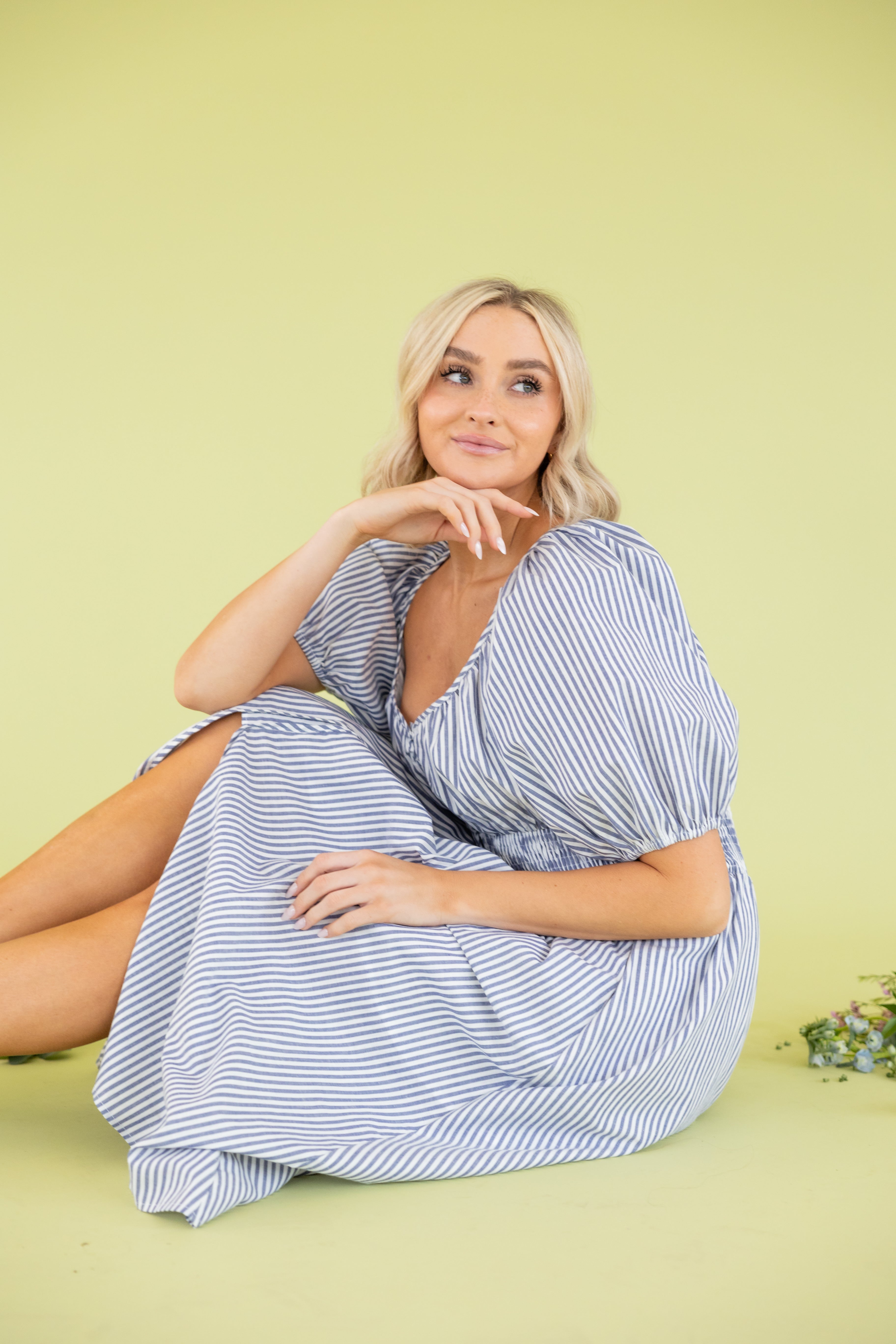 Model is wearing midi blue and white dress with sweetheart neckline. 