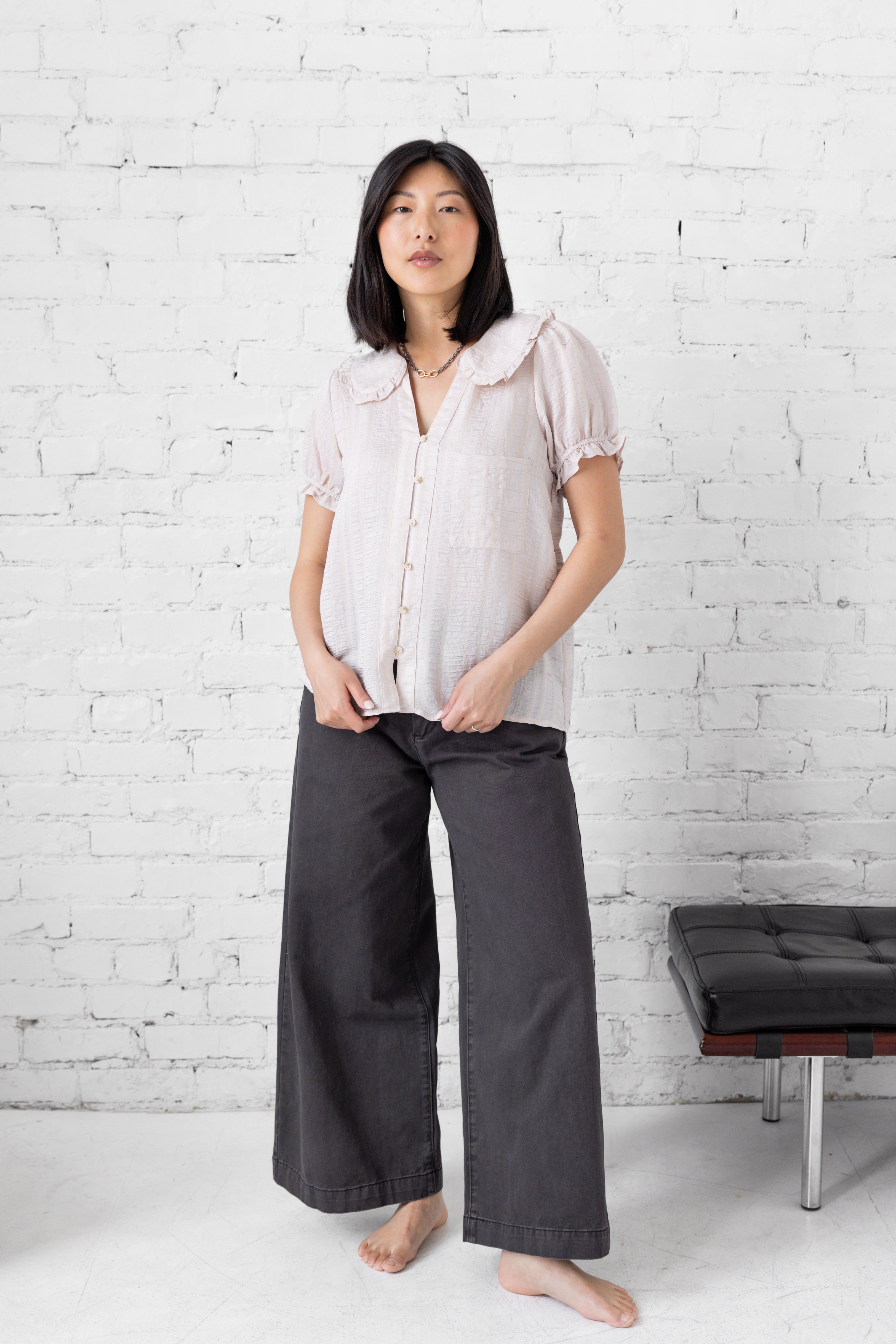 Model is wearing full length blouse with peter pan collar and button up. 