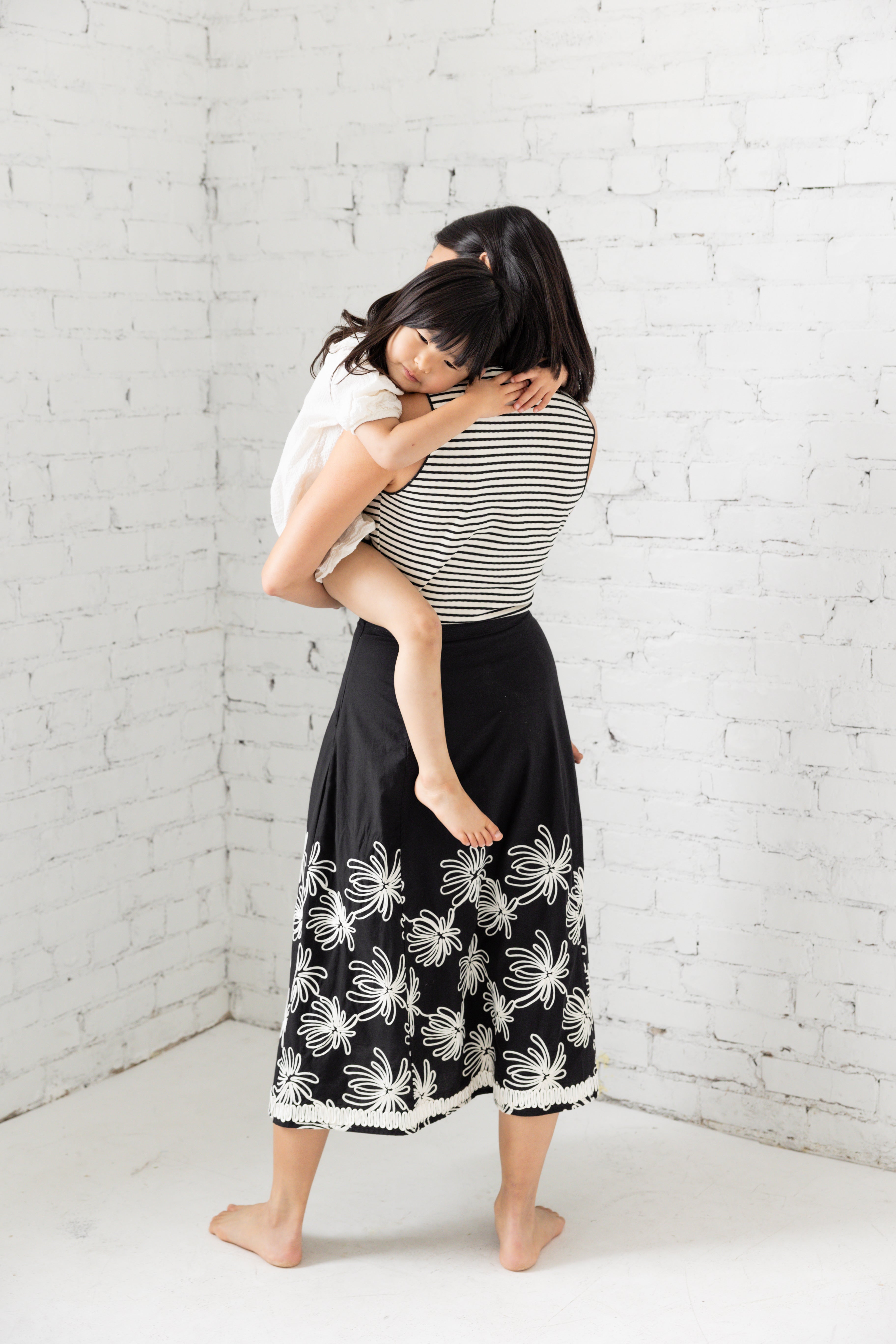 Model is wearing a striped tank top with sweetheart neckline with her children. 