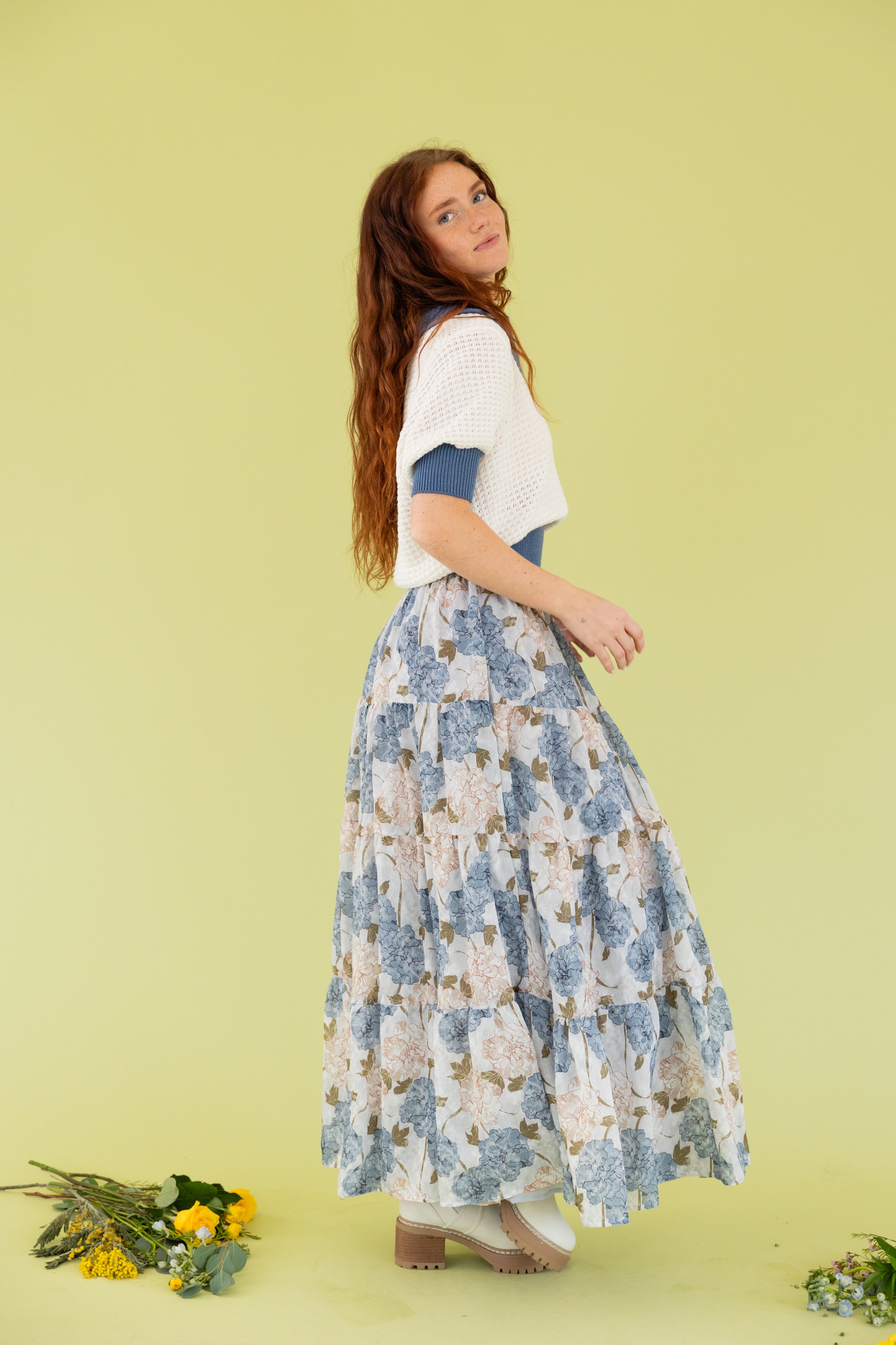 Model is wearing a knit sweater short sleeve top with midi floral blue and white skirt. 