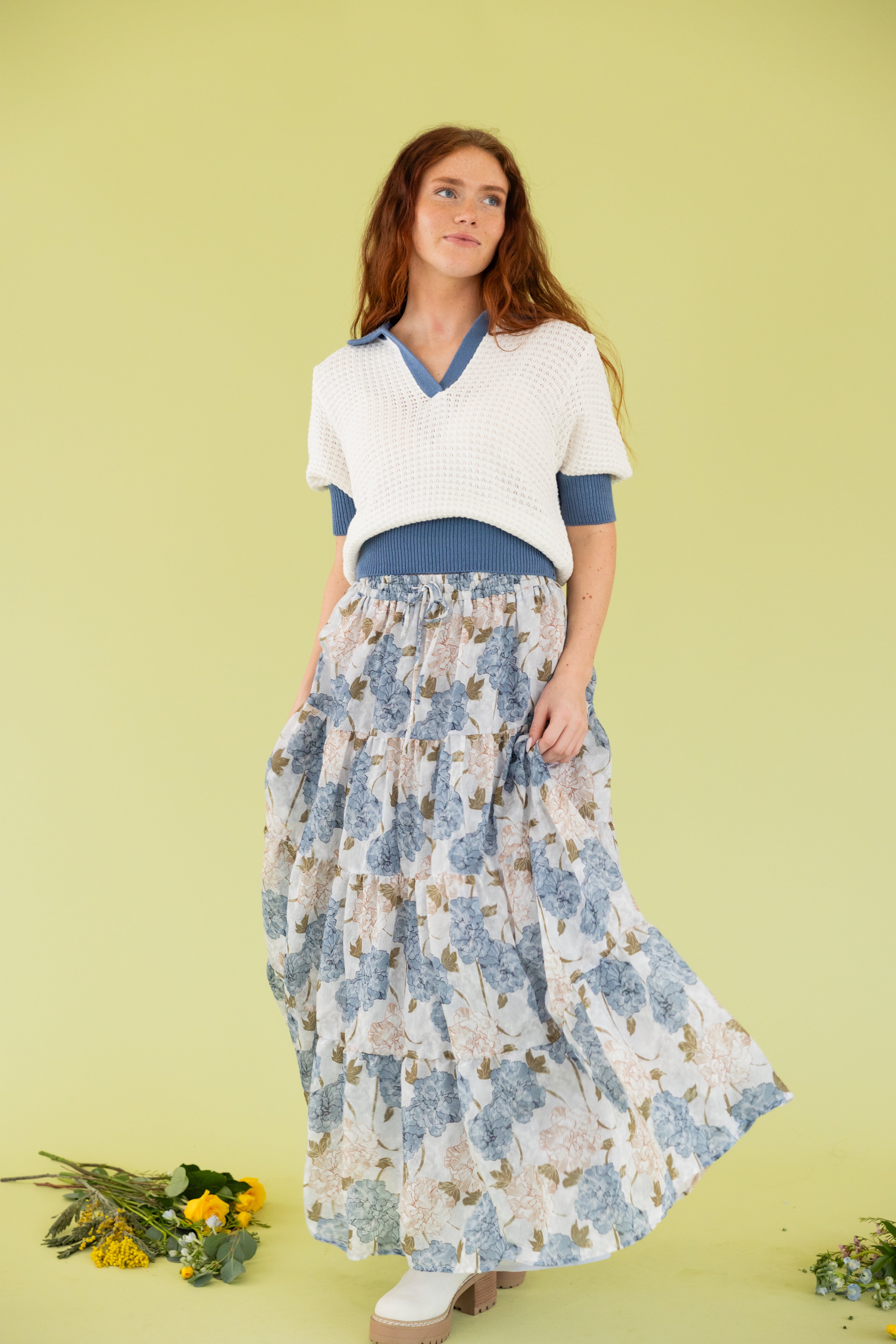 Model is wearing a knit sweater short sleeve top with midi floral blue and white skirt. 