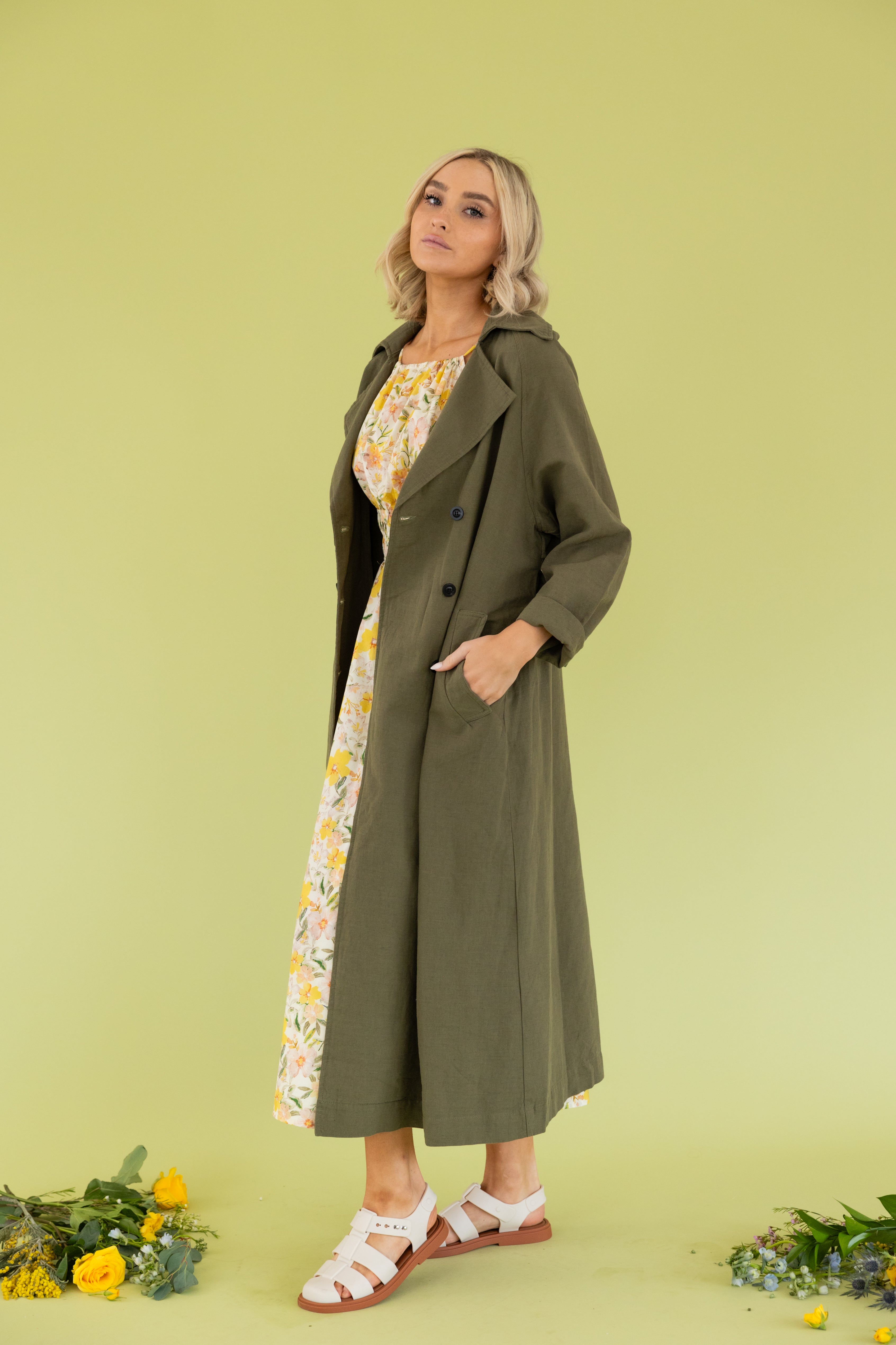 Model is wearing a green maxi trench coat.