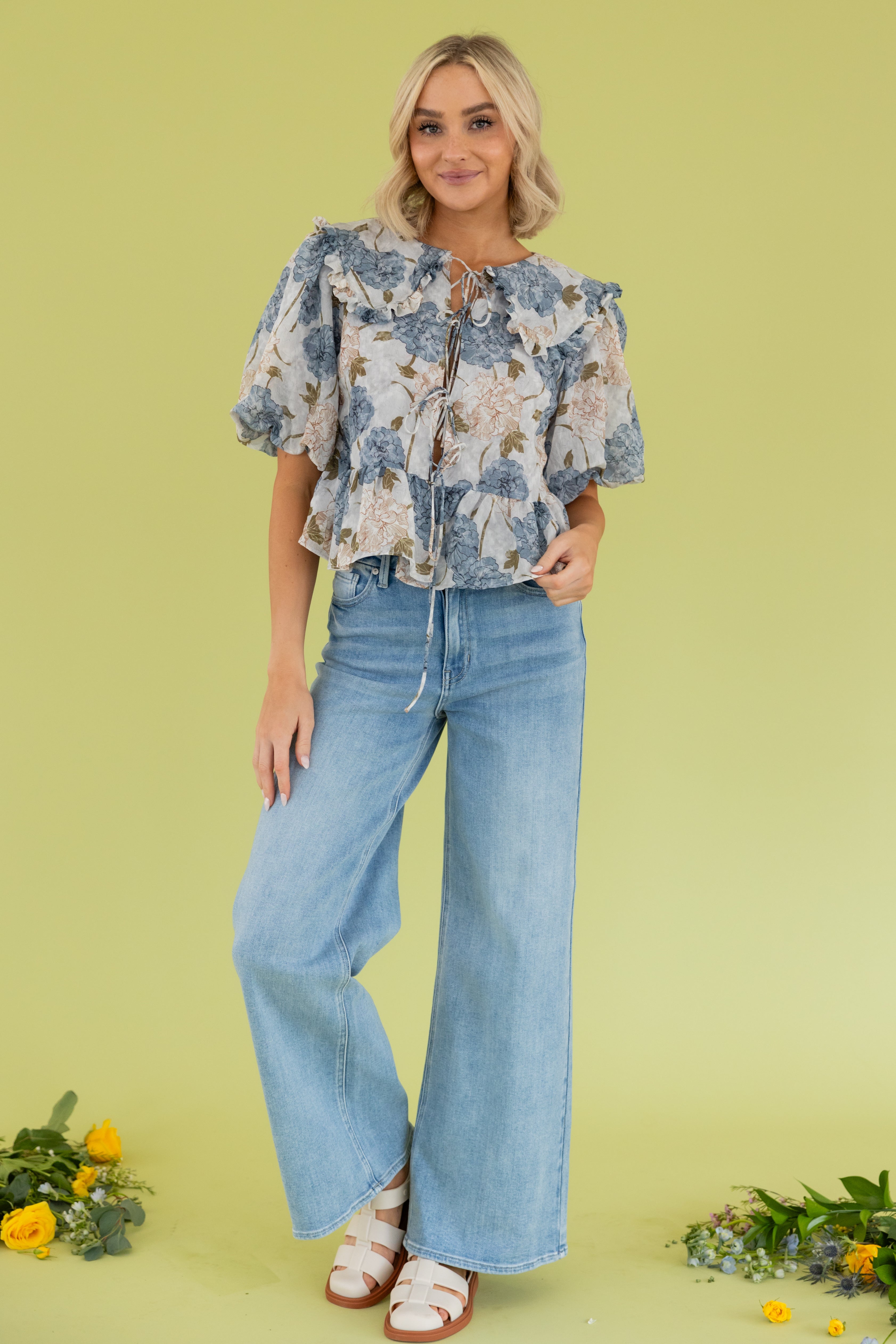 Model is wearing a floral blouse light blue jean.