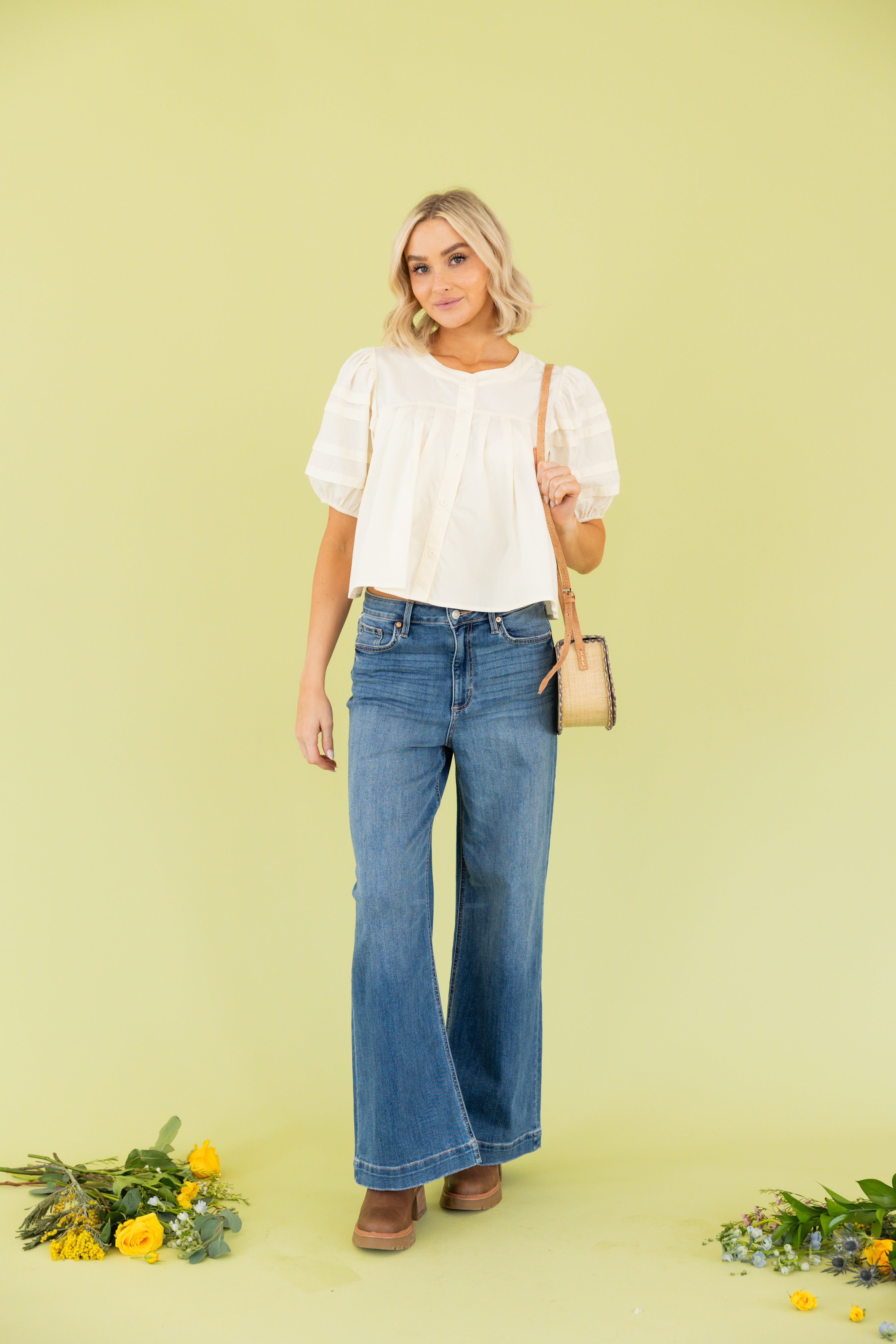 Model is wearing white blouse with wide leg dark wash jean 