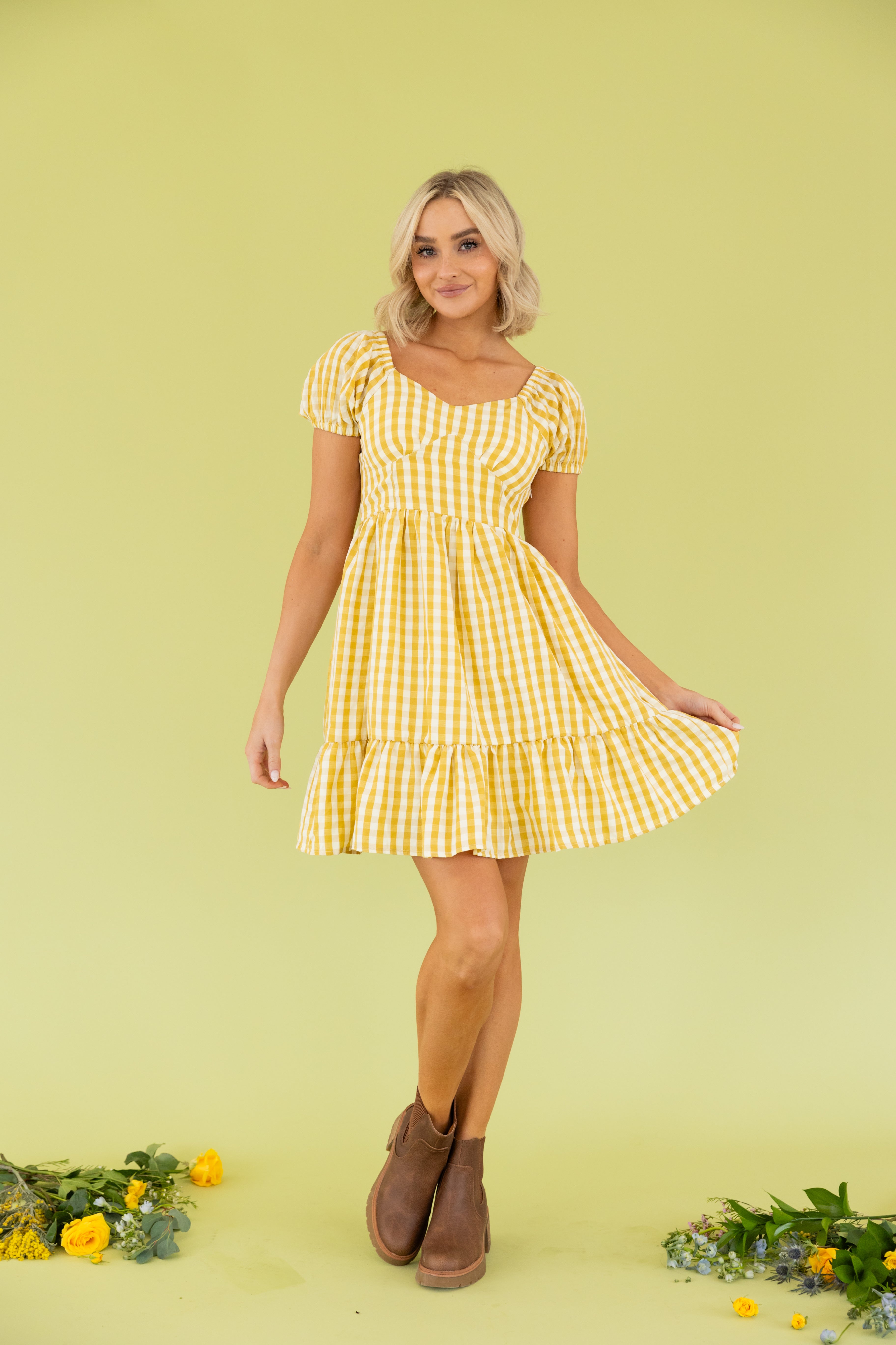 Model is wearing a mini yellow gingham dress.